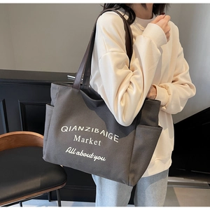 Detail van grijze canvas shopper met een handig zijvak en witte tekstprint op de tas