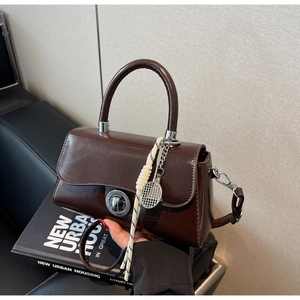 Detail of coffee brown mini bag with metallic lock and unique tennis racket charm