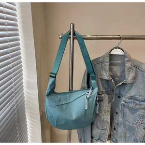 Detailed shot of mint green nylon crescent bag with adjustable strap and woven zipper pull