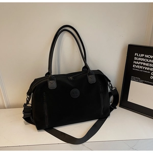 Detailed front view of black nylon travel bag with dual zippers on marble surface