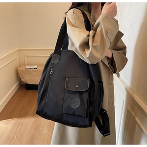 Detail of waterproof Oxford cloth backpack with side pocket and logo on black fabric