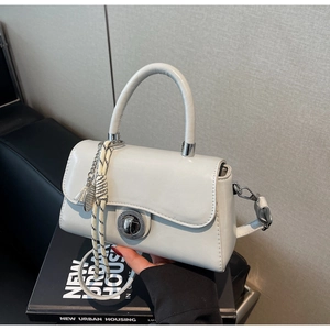 Close-up of minimalist light grey handbag with circular metal lock and woven strap detail
