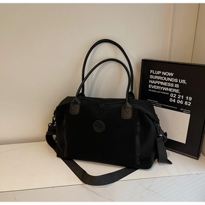 Detail of durable black nylon travel bag featuring side zipper pockets and shoulder strap