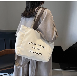 Detail van de gebroken witte canvas shopper met leren handvatten en geprinte letters