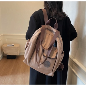 Detail showing the khaki nylon backpack with adjustable straps and front magnetic pocket