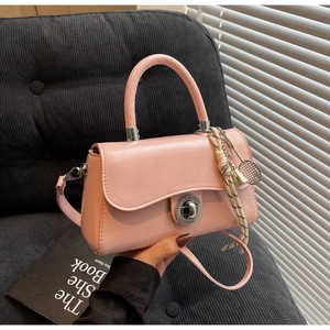Detail of light pink crossbody bag with a silver round twist lock and tennis racket charm