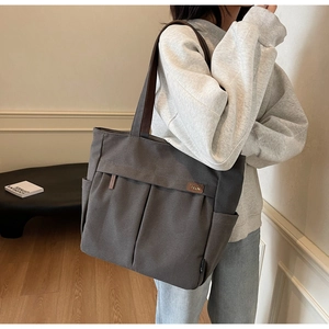 Detail view of large canvas tote bag with front pockets and premium leather logo tag
