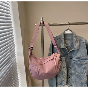 Detailed view of pink nylon half-moon crossbody bag with wide strap and rope zipper