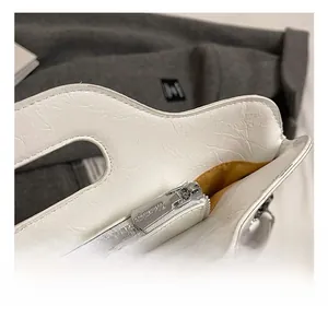 Detail view of white textured leather bucket bag with silver zipper and yellow fabric lining