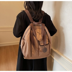 Detail view of khaki nylon backpack featuring multiple pockets and wide fabric straps
