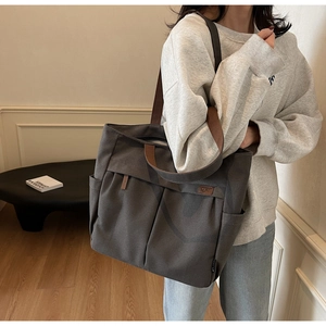 Detail of canvas tote bag with contrast brown straps and front pocket texture