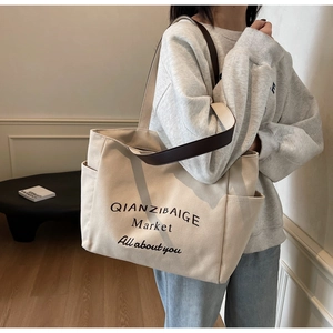 Detail van de gebroken witte canvas tote bag met bruine lederen handvatten en zijzak