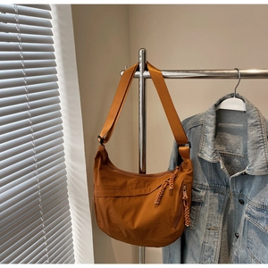 Close-up of caramel nylon crescent bag featuring woven zipper detail and adjustable strap