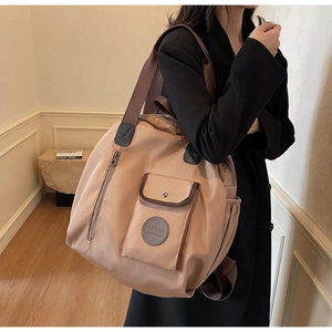 Detail of multi-pocket oxford fabric backpack showing magnetic flap and side zipper