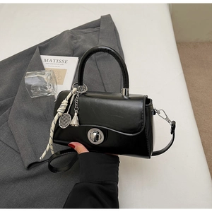 Detail of black glossy leather handbag with silver rotary lock and sports charms