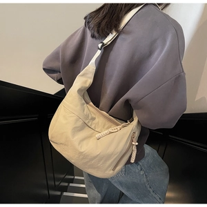 Detail of beige nylon crossbody bag with adjustable wide strap and woven zipper puller