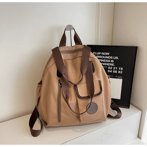 Detail of khaki oxford cloth backpack with multi-pocket design and brown fabric straps
