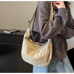 Detail shot of beige nylon crescent bag featuring unique braided rope zipper pulls