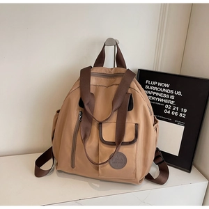 Macro detail of khaki waterproof oxford fabric backpack with leather logo and front pocket