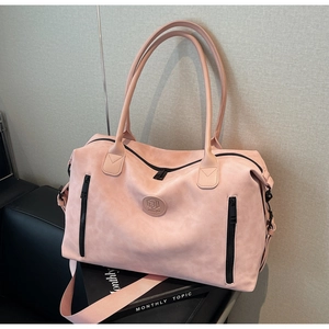 Detail of a large pink travel bag showing the adjustable strap and round logo