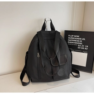 Close-up of black water-resistant nylon backpack with side pockets and logo detail