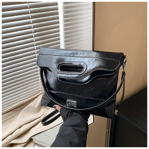 Detail of crinkle texture black glossy bucket bag with unique cutout handle and metal plate