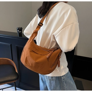 Close-up of caramel nylon crescent bag with woven zipper and adjustable strap
