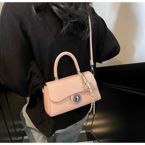 Detail of pink PU leather handbag with silver twist lock and woven tassel accessory