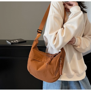 Brown nylon crescent bag detail showing woven zipper pull and adjustable shoulder strap