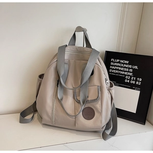 Detail showing the light grey Oxford fabric backpack with a leather logo and side pockets