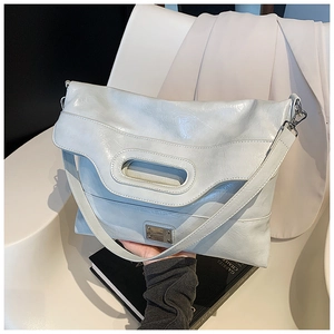 Close-up of light blue polished leather shoulder bag with hollow handle and metal logo
