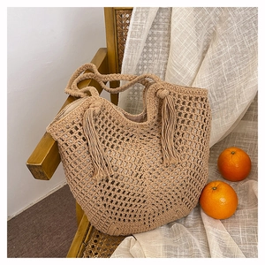 Detail of beige crochet tote bag with long fringe tassels and spiraled woven handles