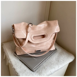 Detail of pink glossy pleated tote bag with oval cutout handle and adjustable silver buckle