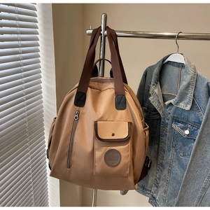 Close-up of khaki waterproof nylon backpack featuring magnetic pocket and leather brand tag