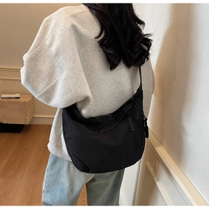 Detail view of large black nylon crescent bag featuring a stylish braided zipper puller