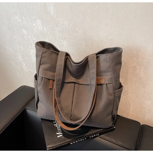 Macro view of charcoal canvas tote bag featuring pleated design and brown faux leather trim
