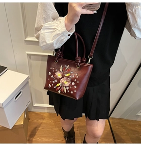 Broderie détaillée de fleurs colorées et d'étoiles sur un sac cabas en cuir bordeaux