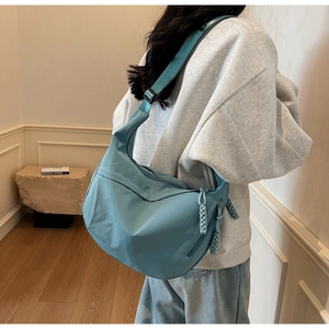 Detail view of the Morandi blue nylon crescent bag showing the adjustable strap and texture