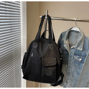 Detail of black nylon multi-purpose backpack hanging with minimalist hardware accents