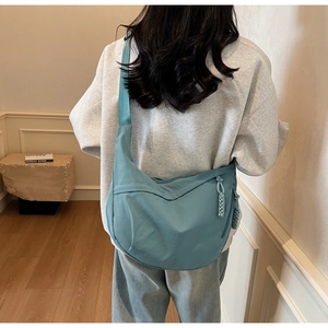 Detailed view of a light blue nylon crescent bag with braided rope zipper on a model