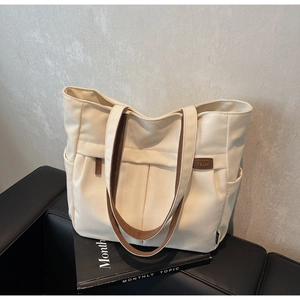 Detail of canvas tote bag showing side storage pocket and brown leather brand label