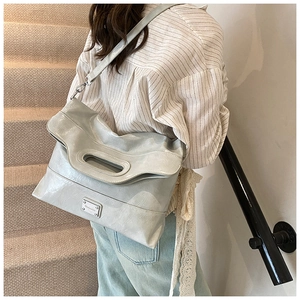 Detail of light grey soft pleated leather tote with unique oval handle and metal logo