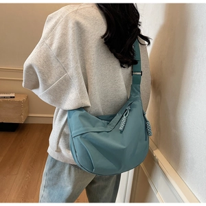 Detail of adjustable strap and zipper on morandi blue-green nylon crescent crossbody bag
