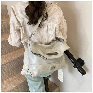 Detail of grey bucket bag with metal logo, leather texture and adjustable shoulder strap