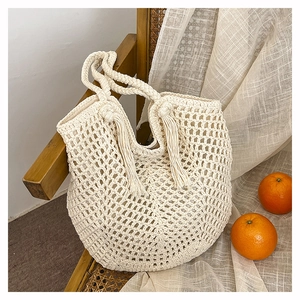 Detailed close-up of ivory crochet tote bag with woven mesh design and tassel accents