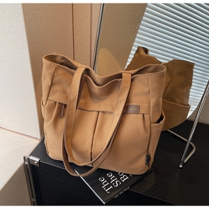 Detail of canvas tote bag showing pleated front pocket and spacious side storage