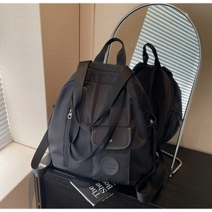 Detail showing multifunctional black nylon backpack with side pockets and smooth finish