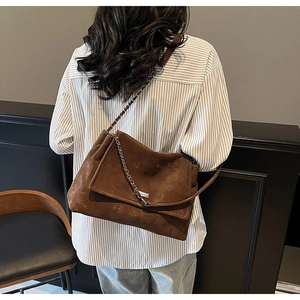 Detail view of deep brown vintage faux leather tote bag with stylish chain strap on model