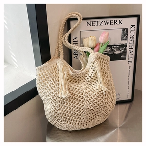 Detailed shot of cream hollow woven tote bag with fringe tassels and braided straps