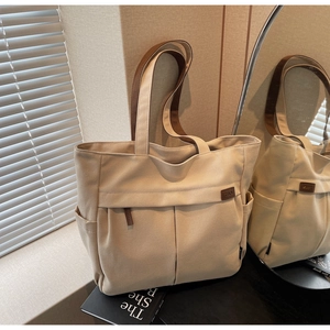 Detail of canvas tote bag showing side pockets and premium brown handle straps